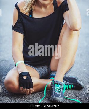 Athletic Woman Sitting Outdoors Taking a Workout Break Stock Photo