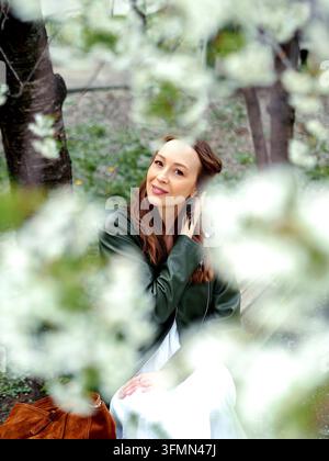 Beautiful caucasian girls with dark hair walking in spring blooming city. Stock Photo