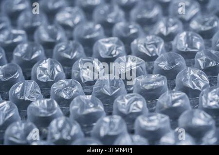 Detailed macro image of bubble wrap showing rows of inflated plastic bubbles with shallow depth of field and soft blue tones. Ideal for concepts of pa Stock Photo