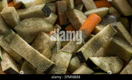 Close view of chopped mixed vegetables with pale green pieces, orange carrot, dark skins, seasoning, and irregular cuts forming a textured food backgr Stock Photo