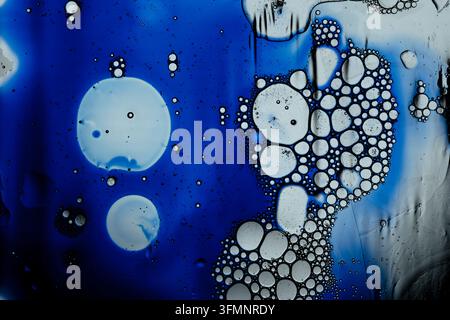 Blue and white oil droplets mixing in water, forming abstract patterns, macro bubbles, and organic textures Stock Photo