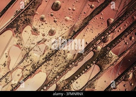 Oil and water forming an abstract macro background, showing bubbles and organic patterns in golden, brown, and pink hues Stock Photo