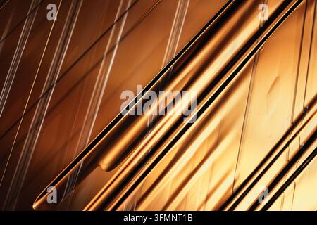 Abstract gold metal surface showing reflections and shadows, forming a geometric pattern with diagonal lines Stock Photo