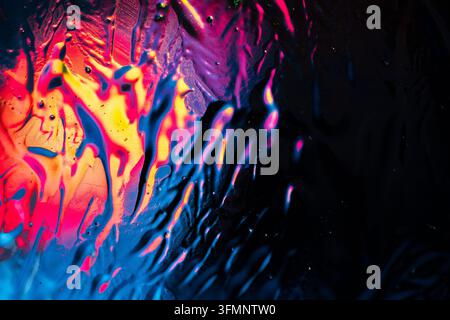 Liquid paint splashes creating a textured background with fluid movement, vivid neon colors, and a dark space for copy Stock Photo