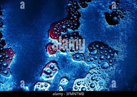 Abstract texture of water droplets, condensation, and bubbles forming on a cold blue surface with icy patches and warm reflections Stock Photo
