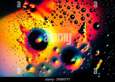 Oil drops on water surface creating colorful abstract macro background with vibrant hues and organic shapes Stock Photo