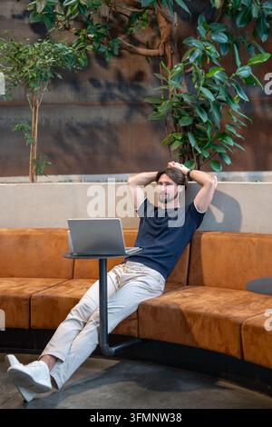 Relaxed businessman taking break after productive work on laptop in cafe, enjoys flexible remote job Stock Photo