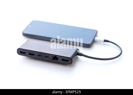 A dark multiport adapter connected via cable to a mobile phone Stock Photo
