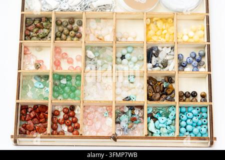 A wooden organizer holds many colorful gemstone beads Stock Photo