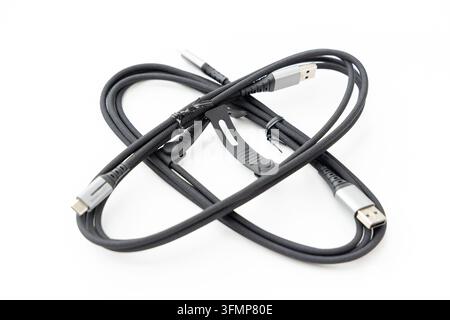 A coiled black braided USB cable sits on white background Stock Photo