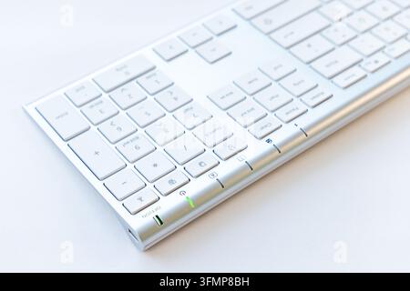A modern silver keyboard rests on a plain surface Stock Photo