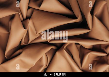 Close-up of stylish crumpled leather fabric in Mocha Mousse, featuring soft folds, rich brown tones, and a tactile textured surface for luxury design Stock Photo