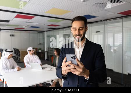 Hispanic businessman, team member checking smartphone during group meeting Stock Photo