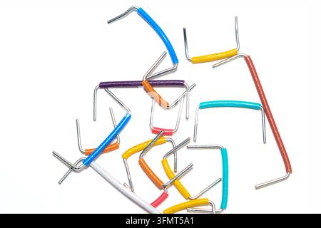 Colorful breadboard jumper wires lying on a white surface, representing circuit connections and hobby electronics Stock Photo