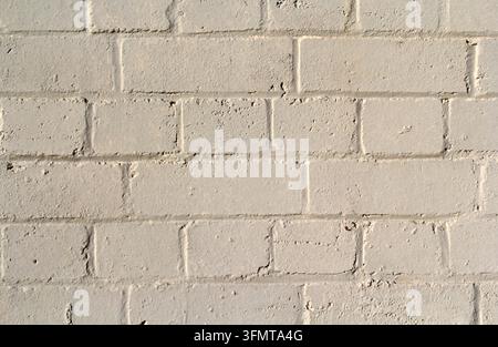 Close-up texture of a painted brick wall with rows of cream bricks, uneven mortar joints, and a slightly weathered surface Stock Photo