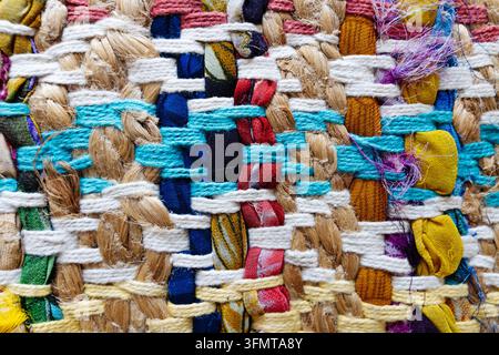 Handwoven rag rug close-up with cotton yarn, jute braids and knotted fabric strips in many colors. Colorful weave texture for interior design Stock Photo