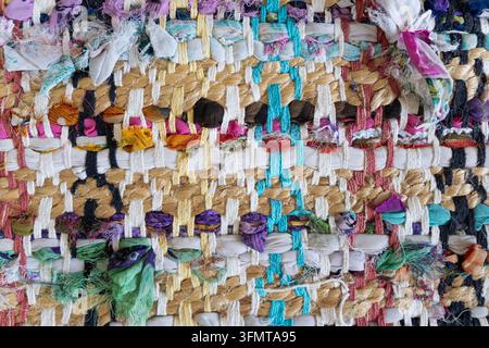 Handwoven rag rug close-up with cotton yarn, jute braids and knotted fabric strips in many colors. Colorful weave texture for interior design Stock Photo