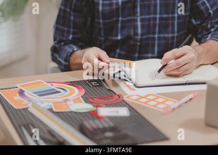 Designer working with color palettes, layout templates, and creative design tools on a desk while planning branding and graphic design projects in a m Stock Photo