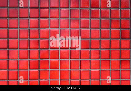 Full-frame texture of small square red ceramic mosaic tiles with dark grout lines forming a neat geometric grid Stock Photo