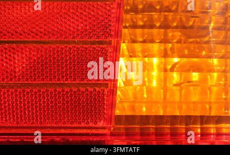 Abstract close-up of a vehicle tail-light assembly showing textured red reflector and orange indicator lens Stock Photo