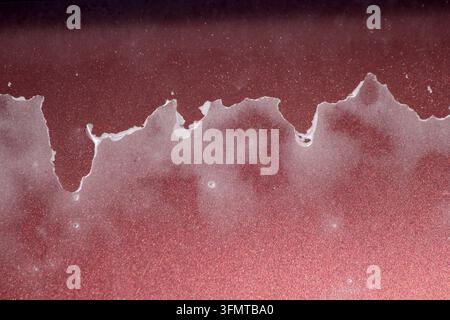 Peeling clear coat and sun-damaged paint lacquer on a maroon metallic automotive surface Stock Photo