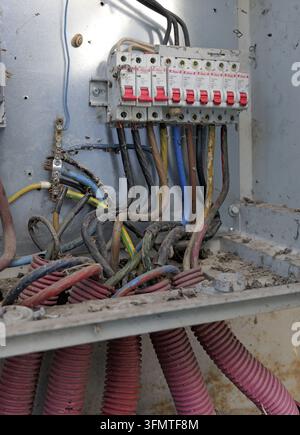 Dirty, neglected electrical panel with dusty circuit breakers, tangled colored wires and exposed cables signaling hazard and repair need. Bulgaria, va Stock Photo