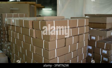 White straps on long brown cardboard boxes stacked high in warehouse, industrial logistics and shipping Stock Photo