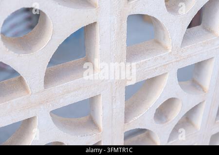 Close up view of a white concrete block wall with geometric openings and textured surface, creating an architectural pattern and abstract structural b Stock Photo