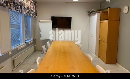 Empty meeting room with long wooden conference table, chairs, television and flip chart Stock Photo