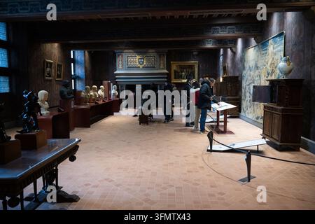 Visitors explore a historic gallery lined with busts, paintings, tapestries and furniture inside the Royal Chateau of Blois, France. Stock Photo