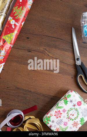 upside view of a table with a wrapped present, ribbons, tape, scissors and christmas themed gift wrap Stock Photo