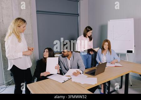 Diverse group of professionals discussing documents and ideas during a company meeting in a modern office environment Stock Photo
