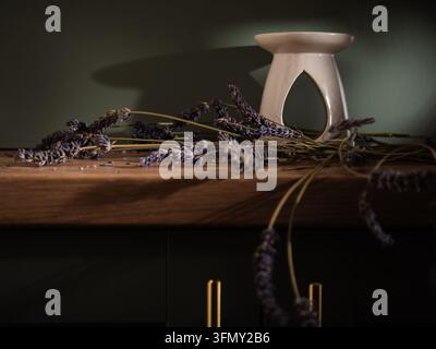 Lavender flowers and oil burner on home green cabinet Stock Photo