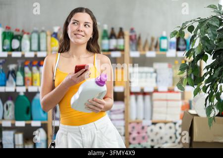Young woman scanning barcode on cleaning product Stock Photo