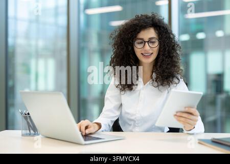 Work Relating Computer Young businesswoman with curly hair and glasses focusing on her work ...