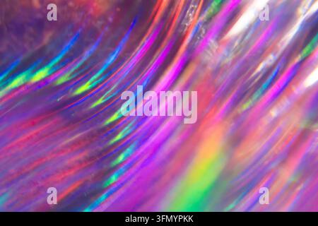 Vibrant abstract background with flowing iridescent holographic light streaks in neon pink, purple, blue and green, creating a luminous futuristic spe Stock Photo