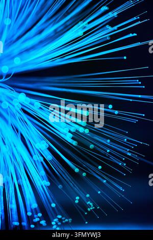 Glowing blue fiber optic strands radiate across a dark background, creating an abstract digital technology concept of fast data transfer, network conn Stock Photo