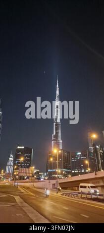A dramatic nighttime photograph showcases the Burj Khalifa dominating the Dubai skyline. The illuminated building stands tall against a dark sky, with Stock Photo