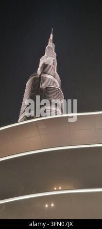 A dramatic nighttime photograph showcases the Burj Khalifa towering against a dark sky. The building is illuminated with a warm glow, creating a sense Stock Photo