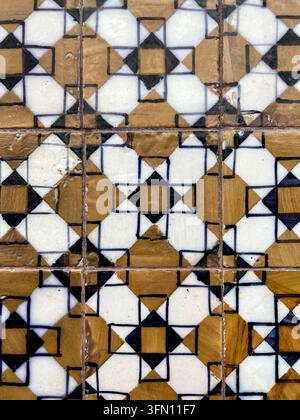 Old Portuguese azulejo tiles with a geometric ochre, white and navy pattern on a wall in Portugal Stock Photo
