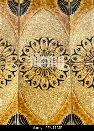 Close-up of glazed brown and ochre azulejo ceramic tiles with a repeating floral pattern on a wall in Portugal Stock Photo