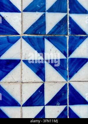 Traditional blue and white azulejo ceramic tiles with a hand-painted geometric triangle pattern on a wall in Portugal Stock Photo