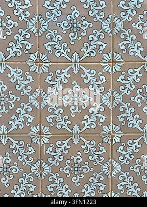 Portuguese azulejo wall tiles in Portugal with white floral scrolls and rosettes on a beige glazed background Stock Photo