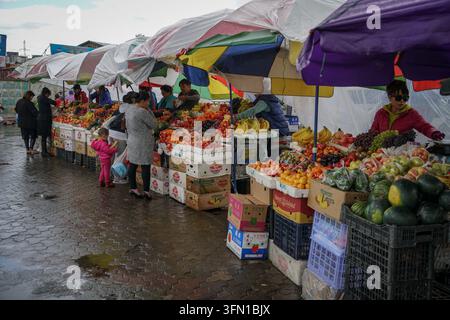 Ulaanbaatar, Mongolia - September 03, 2017: Vendors and customers browse rows of fresh fruits and vegetables displayed on makeshift tables under color Stock Photo