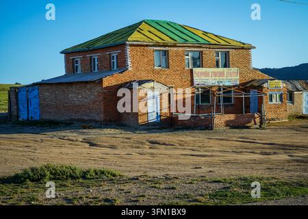 Ulaanbaatar, Mongolia - September 04, 2017: A two-story brick building with a green and yellow striped roof and blue doors stands on a dirt road in th Stock Photo