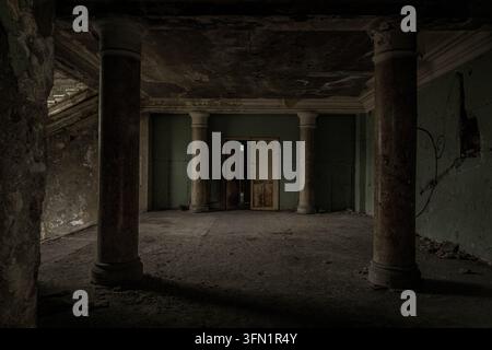 Interior corridor of an abandoned sanatorium in Tskaltubo, Georgia, with a grand doorway, old columns, and decaying Soviet-era architecture. Stock Photo