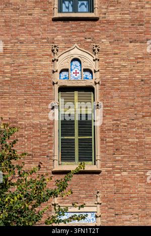 Elegant Modernista window with decorative stonework and blue tile details on a sunny brick facade in Barcelona, Spain. Stock Photo