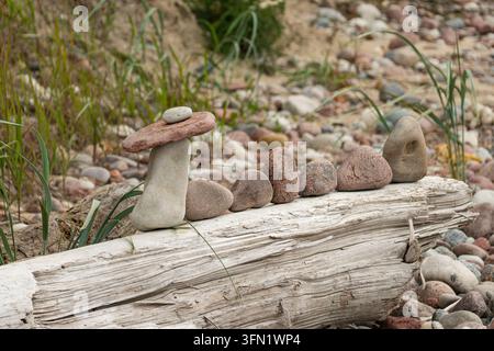 reative stack of sea stones balanced on a driftwood log Stock Photo