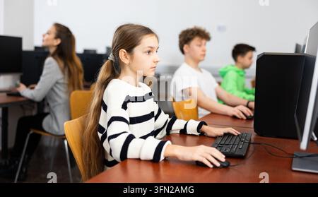 Pupils using computers at lesson, teacher teaching them in class room Stock Photo