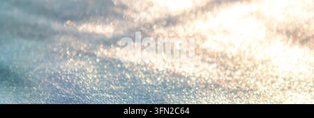 Close-up monochrome texture of granular sand and sparkling pebbles forming an abstract beach pattern Stock Photo